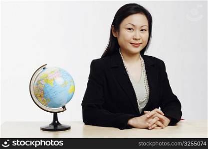 Portrait of a businesswoman sitting in an office with a globe in front of her