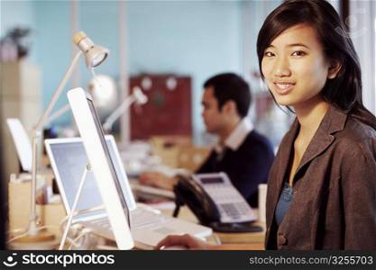 Portrait of a businesswoman sitting in front of a computer in an office and smiling