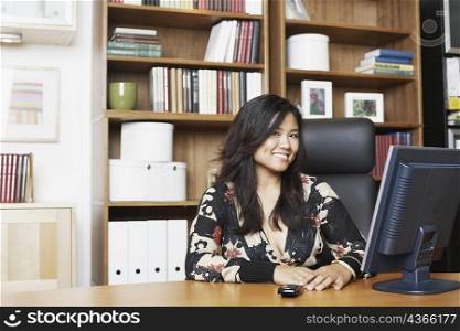 Portrait of a businesswoman sitting in front of a computer smiling