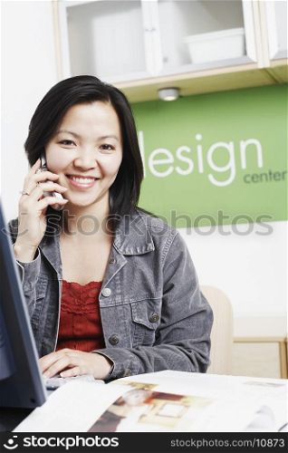 Portrait of a businesswoman sitting in front of a computer using a mobile phone