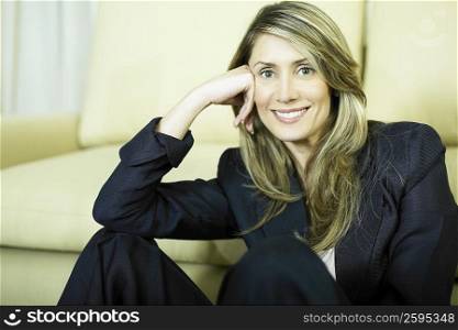 Portrait of a businesswoman sitting in front of a couch and smiling