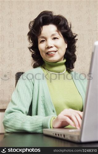 Portrait of a businesswoman sitting in front of a laptop smiling