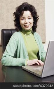 Portrait of a businesswoman sitting in front of a laptop smiling