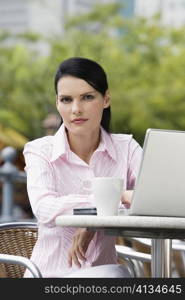 Portrait of a businesswoman sitting on a chair and using a laptop
