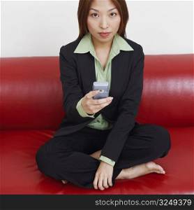 Portrait of a businesswoman sitting on a couch and holding a mobile phone