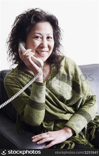 Portrait of a businesswoman sitting on a couch using a telephone