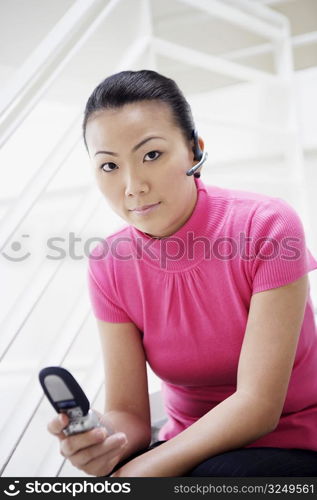 Portrait of a businesswoman sitting on a staircase and holding a mobile phone