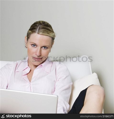 Portrait of a businesswoman sitting on the bed holding a laptop