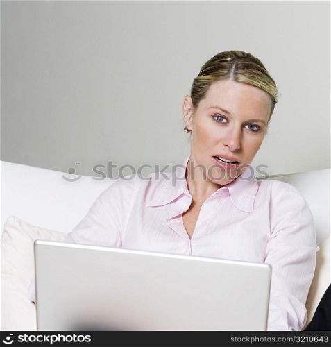 Portrait of a businesswoman sitting on the bed holding a laptop