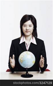 Portrait of a businesswoman sitting with a globe in front of him