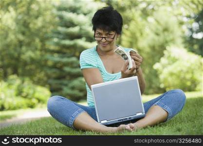 Portrait of a businesswoman sitting with a laptop and showing US paper currency