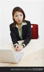 Portrait of a businesswoman sitting with a laptop in a board room