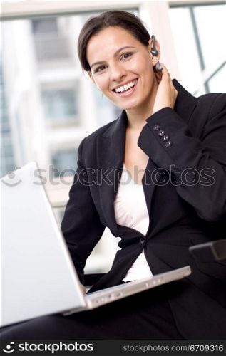 Portrait of a businesswoman sitting with a laptop on her lap and smiling