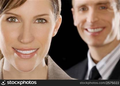 Portrait of a businesswoman smiling with a businessman behind her