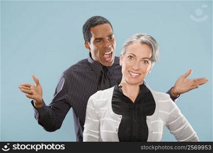 Portrait of a businesswoman smiling with a businessman shouting at her