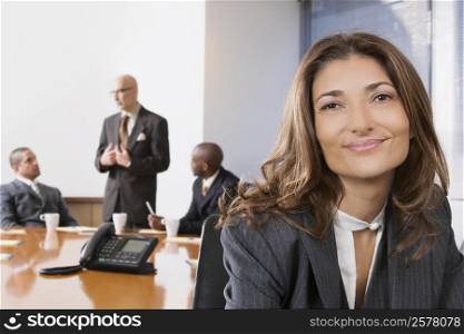 Portrait of a businesswoman smiling with other business executives in a board room