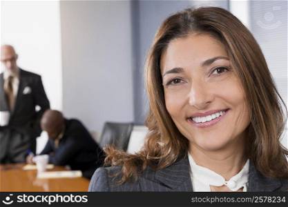 Portrait of a businesswoman smiling with other business executives in a board room