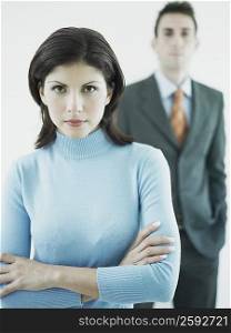 Portrait of a businesswoman standing with his arms crossed and a businessman standing behind her