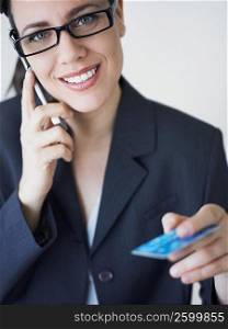 Portrait of a businesswoman talking on a mobile phone and holding a credit card