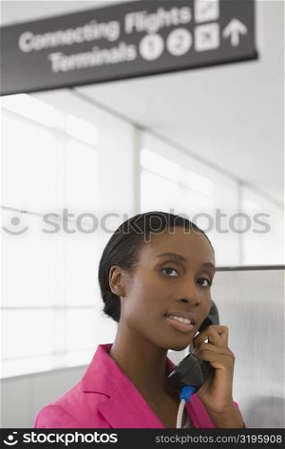 Portrait of a businesswoman talking on a pay phone and smiling