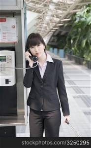 Portrait of a businesswoman talking on a public phone at an airport