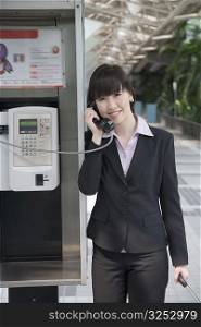 Portrait of a businesswoman talking on a public phone at an airport