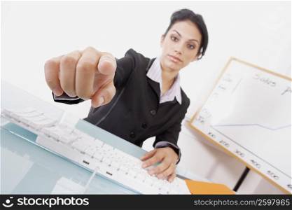Portrait of a businesswoman using a computer keyboard and pointing forward