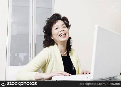 Portrait of a businesswoman using a laptop laughing