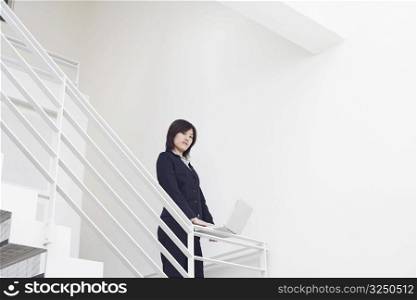Portrait of a businesswoman using a laptop on the staircase