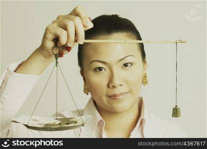 Portrait of a businesswoman weighing paper currency with coins on a weighing scale