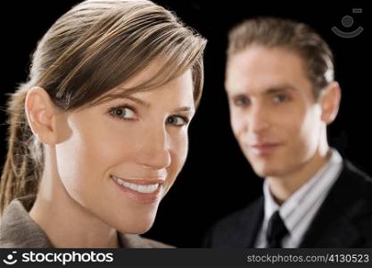 Portrait of a businesswoman with a businessman behind her