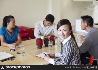 Portrait of a businesswoman with three business executives seated at a conference table