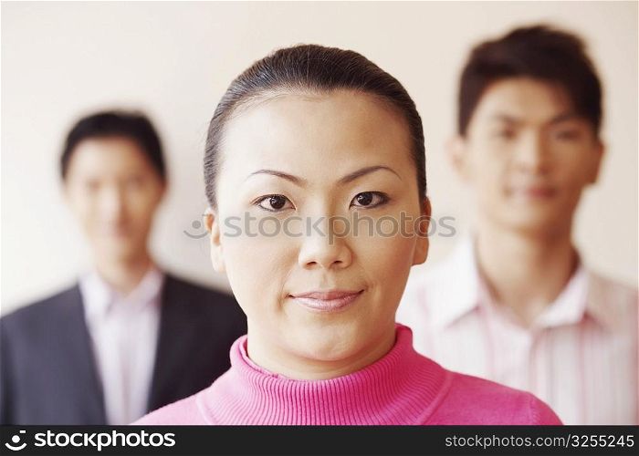 Portrait of a businesswoman with two businessmen in the background