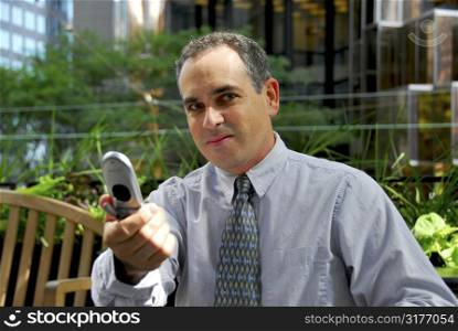 Portrait of a busy businessman in the city holding a cell phone