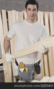 Portrait of a carpenter holding a wooden plank
