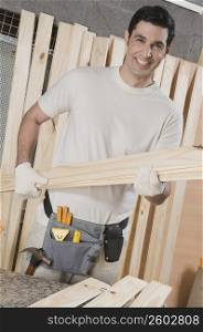 Portrait of a carpenter holding a wooden plank and smiling