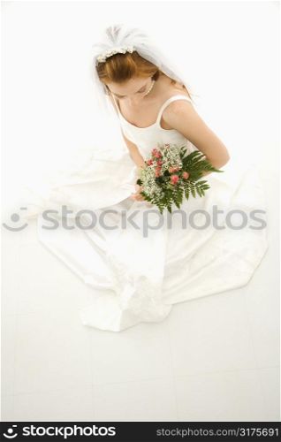 Portrait of a Caucasian bride holding bouquet.