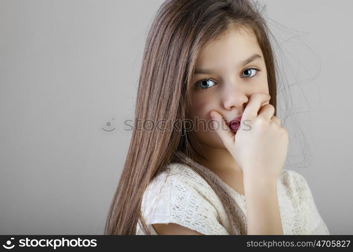 Portrait of a charming brunette little girl, isolated on gray background