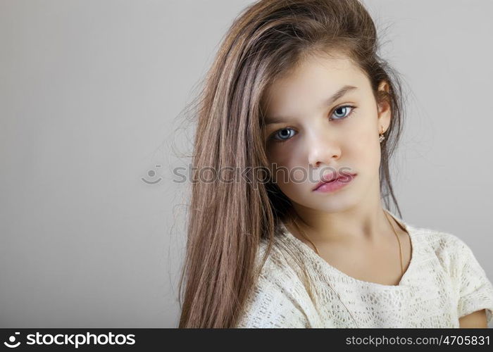 Portrait of a charming brunette little girl, isolated on gray background