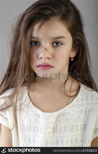 Portrait of a charming brunette little girl, isolated on gray background