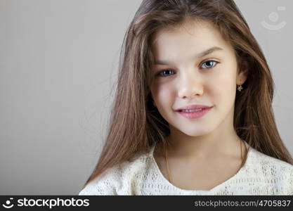 Portrait of a charming brunette little girl, isolated on gray background