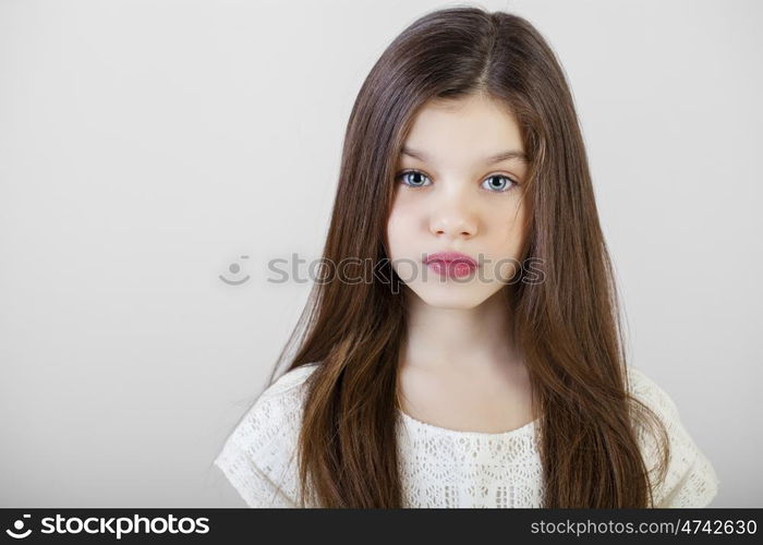 Portrait of a charming brunette little girl, isolated on gray background