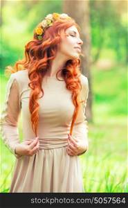 Portrait of a charming dreamy young woman in spring forest, girl wearing beautiful flower wreath on curly red hair, spring time fashion