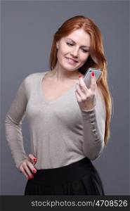 Portrait of a charming young female text messaging on cellphone against grey background