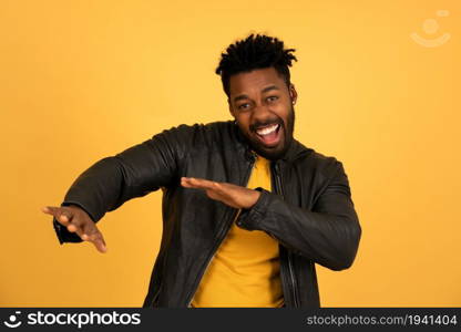 Portrait of a cheerful afro man dancing while standing against an isolated background.