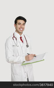 Portrait of a cheerful Indian male doctor holding a medical chart over light gray background