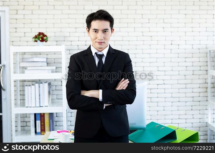 Portrait of a cheerful mature asian young businessman wear a business suit of man in blue jacket and blue shirt looking at the window In the office room background.