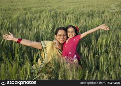 Portrait of a cheerful mother and daughter with arms out