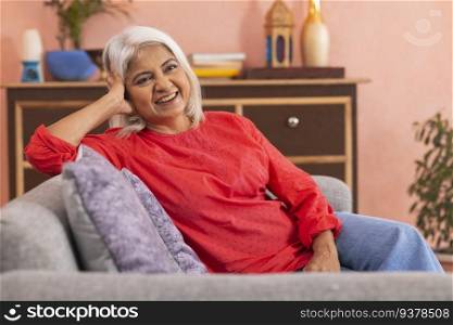 Portrait of a cheerful old woman relaxing on sofa in living room
