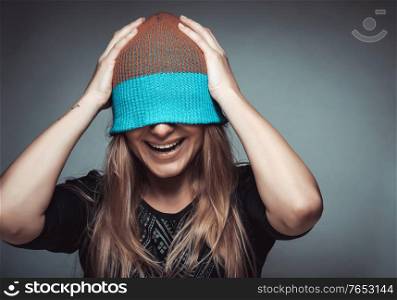 Portrait of a cheerful smiling female student wearing a hat on her face, playing and having fun, concept of enjoying life, funky youth, street urban style fashion for youngsters